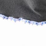 Close-up of a dark gray fabric item with a decorative ruffled trim featuring a light blue and white pattern, shown against a plain white background.