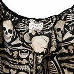 Close-up of a black garment with an all-over cream skeleton print, featuring a ruffled neckline and a visible fabric label that reads 'Letter Left London'.