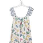 A baby romper hanging on a clear plastic hanger against a white wall. The romper features a cream-colored body with a colorful dinosaur print in shades of blue, green, yellow, and pink, and has light blue and white gingham checkered shoulder straps.