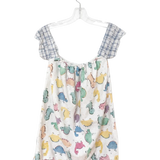A children's sleeveless romper hanging on a clear plastic hanger against a plain white background. The romper has a white base with a colorful print of cartoon dinosaurs and has blue-and-white plaid shoulder straps.
