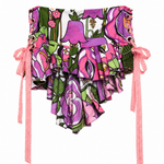 A ruffled bikini bottom featuring a vibrant pink, purple, and green floral and botanical print, with pink beaded side ties hanging down on a white background.