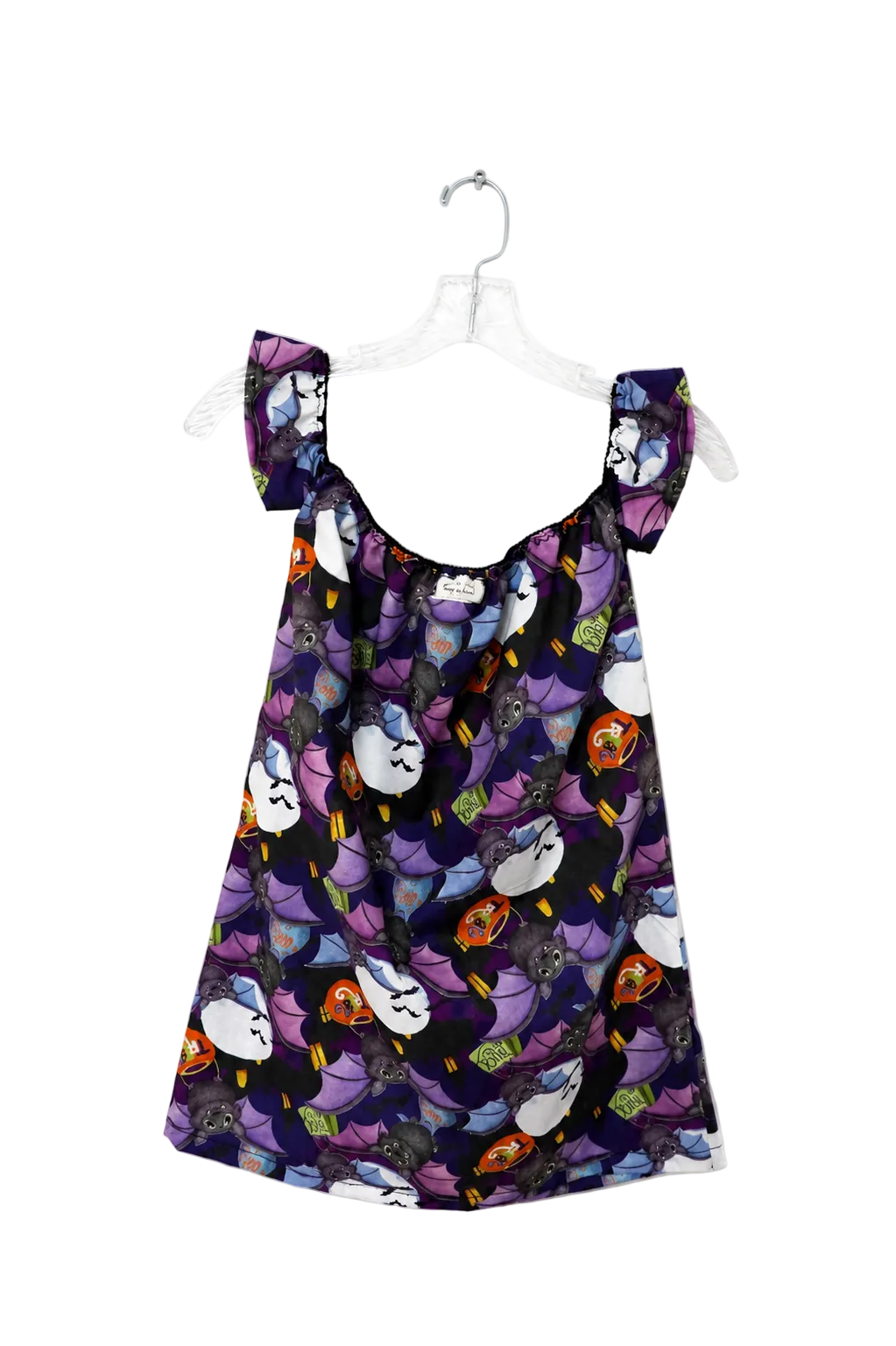 A sleeveless babydoll dress with a dark purple and black background, featuring a playful print of cartoon cats in white, purple, orange, and yellow. The dress has ruffled shoulder straps and is displayed on a clear plastic hanger against a plain white background.