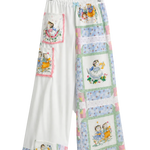 White wide-leg pants with a patchwork quilt design featuring vintage illustrations of children, hanging on a clear plastic hanger against a white background.