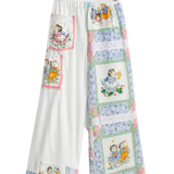 White wide-leg pants with a patchwork quilt design featuring vintage illustrations of children, hanging on a clear plastic hanger against a white background.