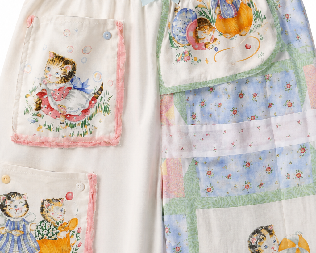 A pair of children's patchwork pajama pants featuring whimsical cartoon animal and girl illustrations, split down the middle with one side in cream fabric with pink-trimmed pockets and the other side in a pastel patchwork design.