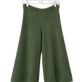 A pair of olive green wide-leg cropped pants hanging from a clear plastic hanger against a plain white wall.
