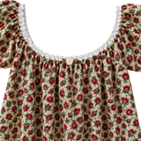 A close-up of a floral off-the-shoulder top with ruffled sleeves, a white lace neckline, and a small decorative button at the center, shown against a plain light background.