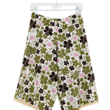 A pair of women's wide-leg shorts with a retro floral pattern featuring olive green, dark brown, and pink flowers on a cream background, hanging on a clear plastic hanger against a white wall.