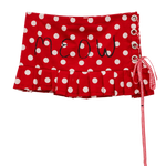 Red and white polka dot skirt with 'MEOW' embroidered on the front, featuring a ruffled hem, side lace-up closure with metal eyelets, and a red-and-white gingham ribbon tie.