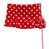 Red and white polka dot skirt with 'MEOW' embroidered on the front, featuring a ruffled hem, side lace-up closure with metal eyelets, and a red-and-white gingham ribbon tie.