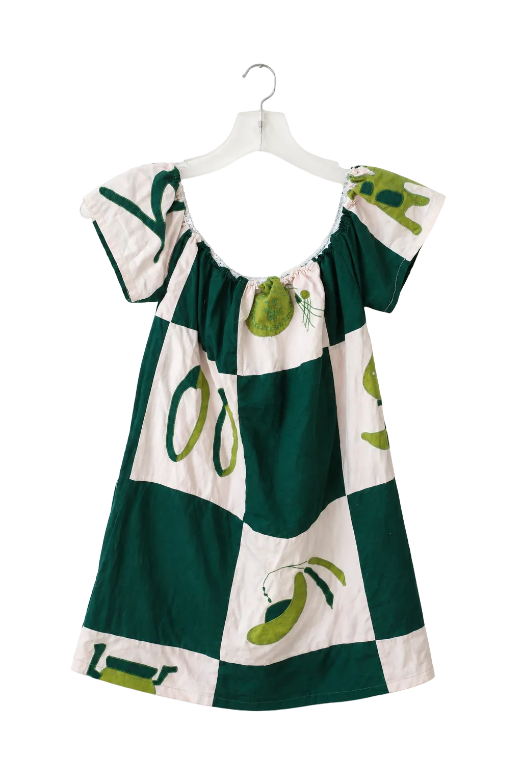 A short-sleeve dress with a green and white checkered pattern and olive illustrations, hanging on a white plastic hanger against a plain white wall.