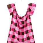 A pink and brown checkered top with ruffled cap sleeves, hanging on a white plastic hanger against a plain white wall.