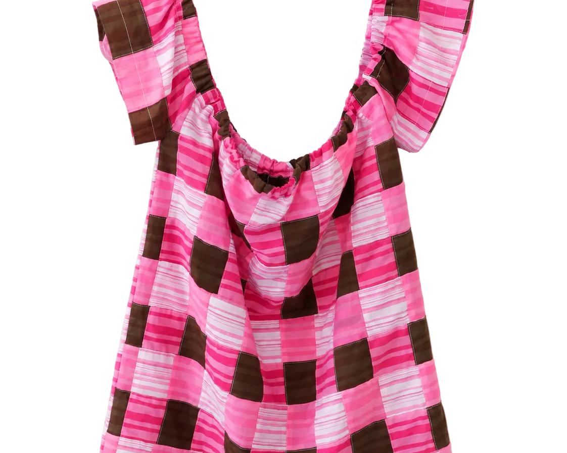 A pink and brown checkered top with ruffled cap sleeves, hanging on a white plastic hanger against a plain white wall.
