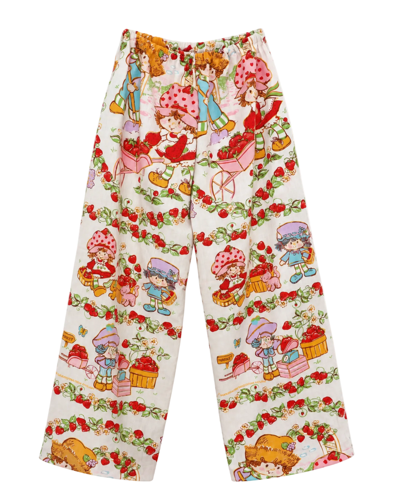 A pair of Strawberry Shortcake  1983 wide-leg pants featuring an all-over Strawberry Shortcake character print on a white background, shown flat against a white studio background.