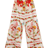A pair of 1983 wide-leg cropped pants featuring a colorful Strawberry Shortcake-themed print with red strawberries, cartoon characters, and text on a cream background.