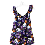 A sleeveless baby/toddler dress with ruffled shoulder straps, featuring a purple and black Halloween print of bats, ghosts, and jack-o'-lanterns, hanging on a white plastic hanger against a white background.